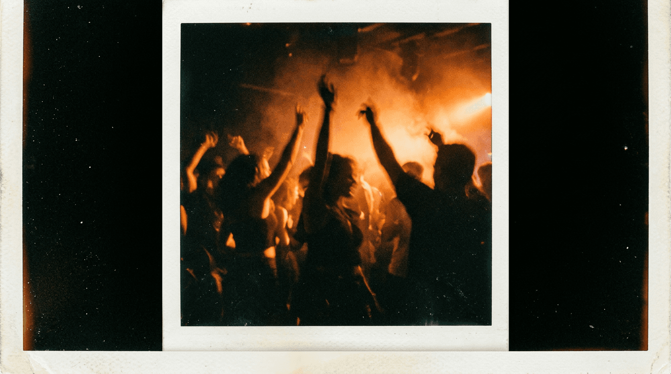 A crowded dancefloor lit by an orange strobe, arms up, motion blur.